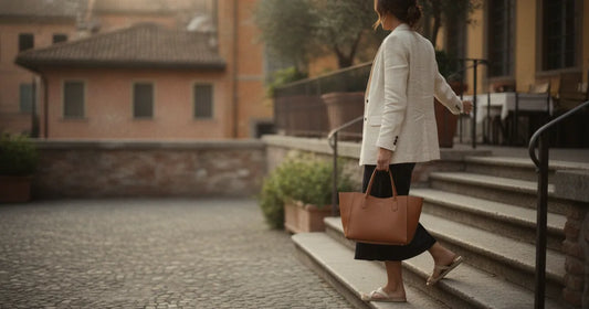 Woman holding a structured leather tote, shot from behind, stepping off a Milan trattoria terrace at sunset