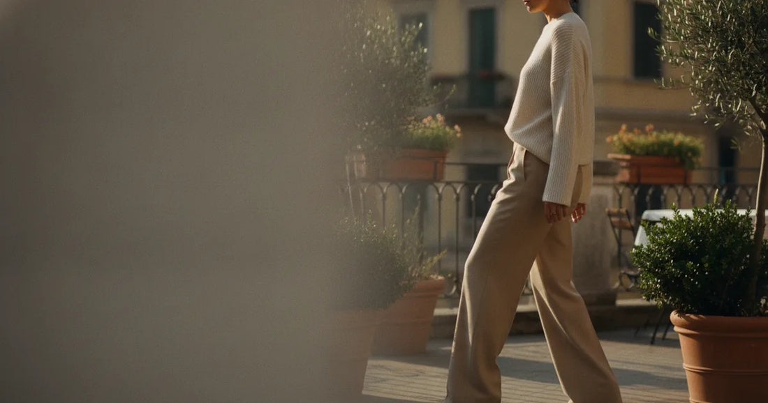 Woman in a minimalist neutral-toned outfit — a relaxed knit and tailored trousers, stepping off a Milan trattoria terrace...