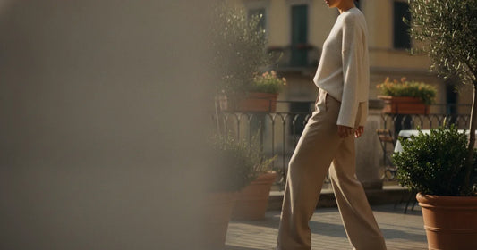 Woman in a minimalist neutral-toned outfit — a relaxed knit and tailored trousers, stepping off a Milan trattoria terrace...
